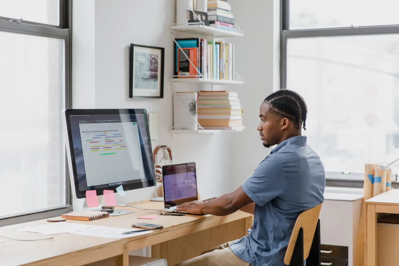 Person working at a desk with a computer and laptop