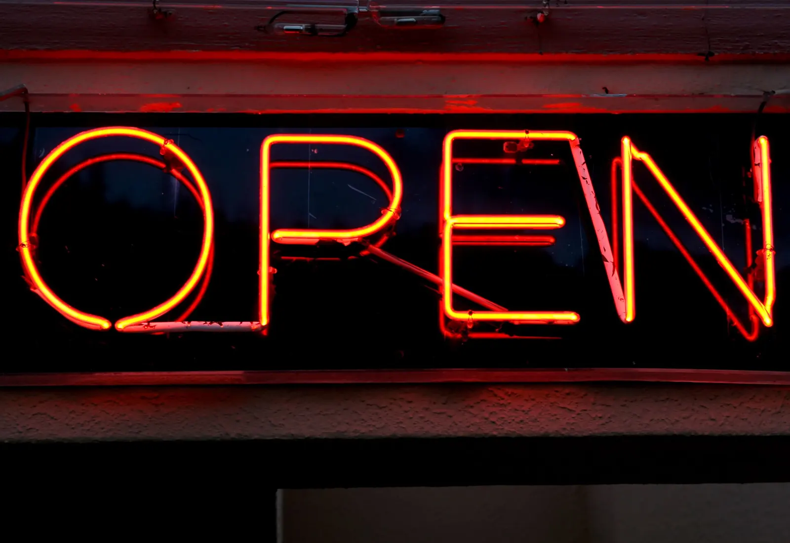 A glowing orange OPEN sign in a shop window at night